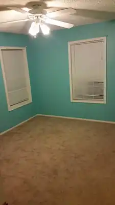 Bedroom painted teal with white trim and ceiling fan